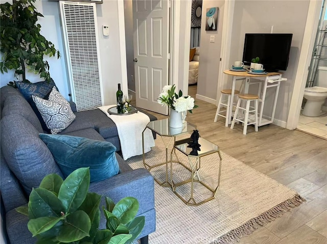 living area with baseboards, a heating unit, and wood finished floors