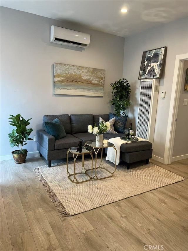 living room with wood finished floors, a heating unit, baseboards, and a wall unit AC