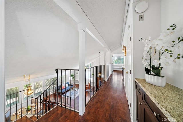 corridor with an upstairs landing, a chandelier, wood finished floors, and lofted ceiling
