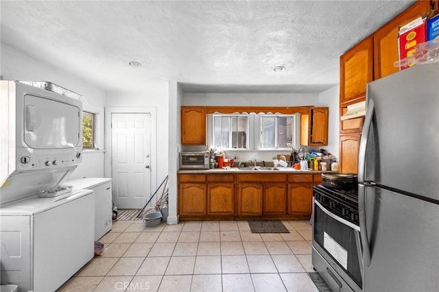 844W 105th St, Los Angeles, CA 90044 - kitchen with appliances with stainless steel finishes, stacked washer / dryer, a sink, and brown cabinetry