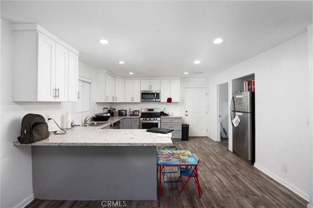 844W 105th St, Los Angeles, CA 90044 - kitchen featuring appliances with stainless steel finishes, a peninsula, recessed lighting, dark wood finished floors, and baseboards