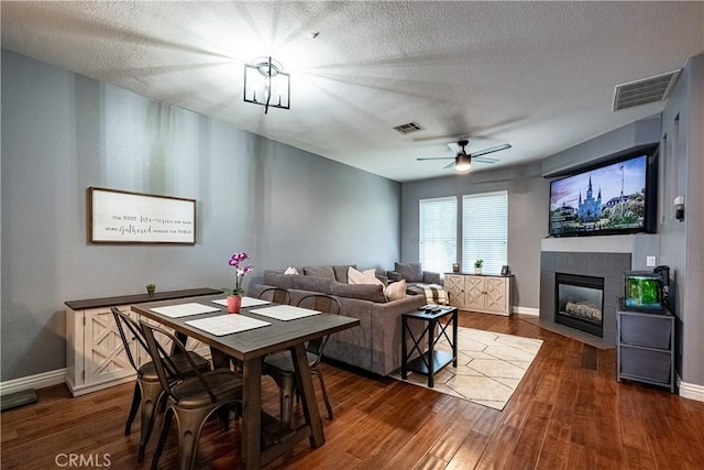 7 Burlingame Ln, Aliso Viejo, CA 92656 - dining area with dark wood-style floors, a tile fireplace, baseboards, a ceiling fan, and a textured ceiling