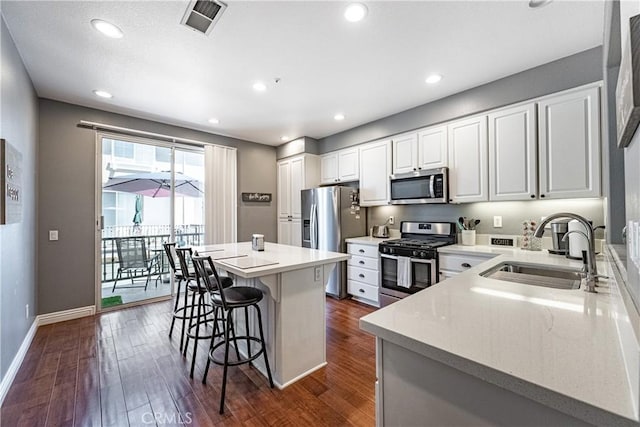 7 Burlingame Ln, Aliso Viejo, CA 92656 - kitchen with appliances with stainless steel finishes, a sink, a breakfast bar, dark wood finished floors, and a center island