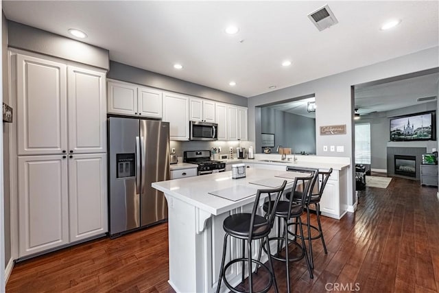 7 Burlingame Ln, Aliso Viejo, CA 92656 - kitchen featuring stainless steel appliances, a breakfast bar, dark wood-style flooring, light countertops, and a ceiling fan