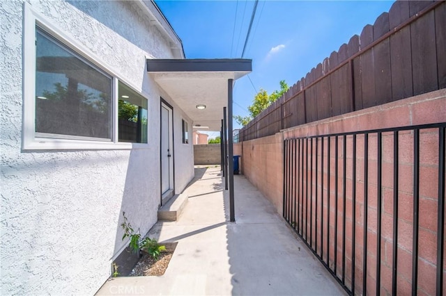view of side of home with fence and stucco siding