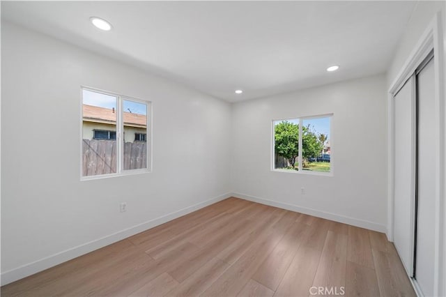 unfurnished bedroom with baseboards, a closet, recessed lighting, and light wood-style flooring