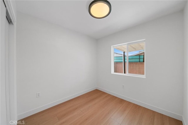 spare room featuring baseboards and light wood finished floors