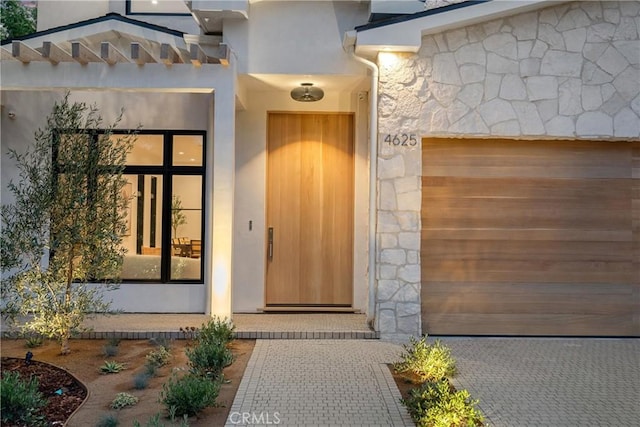 doorway to property featuring stucco siding and stone siding