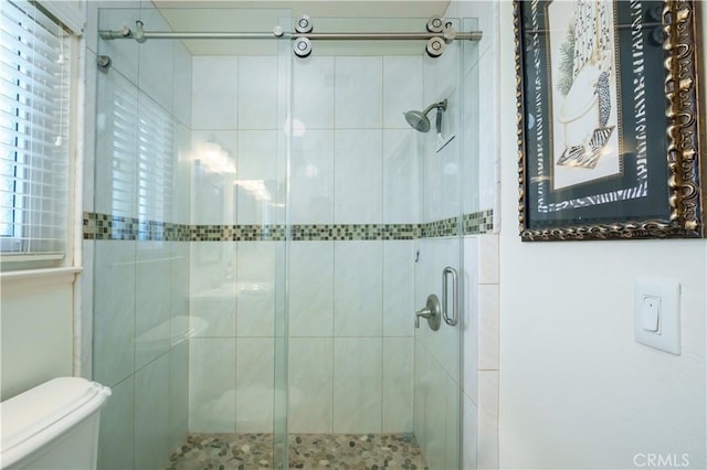 bathroom featuring toilet and a shower stall