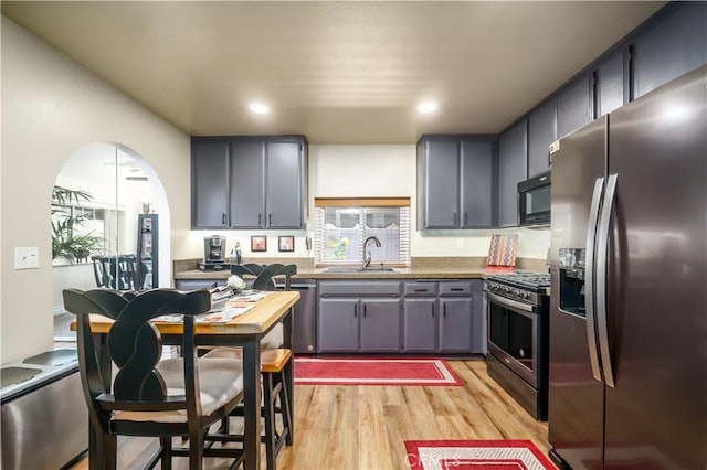 kitchen with stainless steel appliances, a sink, light wood finished floors, recessed lighting, and gray cabinetry