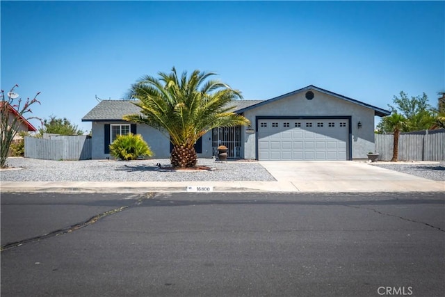 view of front facade with a garage, driveway, fence, and stucco siding