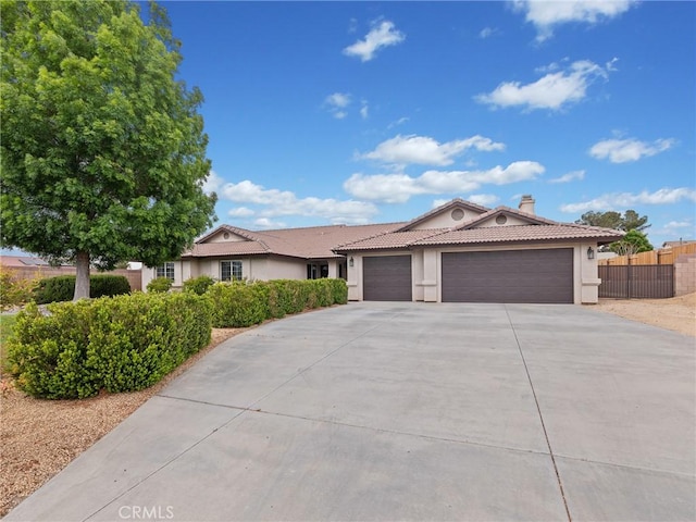 ranch-style house featuring fence, a tile roof, a garage, stucco siding, and driveway