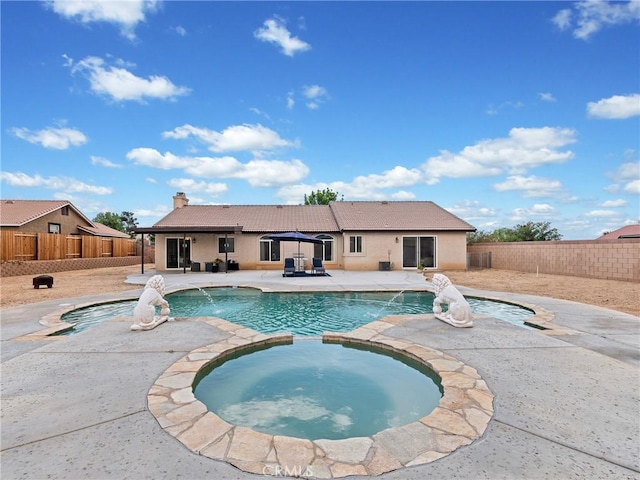 view of pool featuring a fenced backyard, a pool with connected hot tub, and a patio area