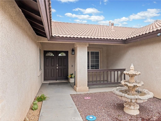 view of exterior entry featuring stucco siding and a tiled roof