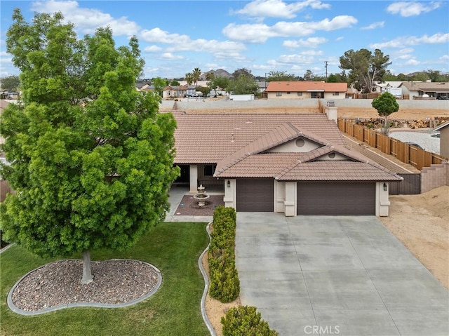 mediterranean / spanish-style home with an attached garage, a tile roof, stucco siding, a front yard, and driveway