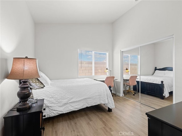 bedroom with baseboards, light wood-style flooring, and a closet