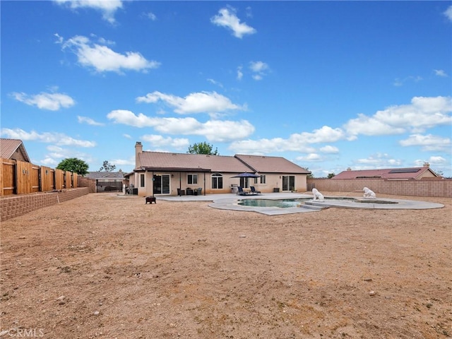 back of house with a fenced in pool, a patio, a chimney, and a fenced backyard