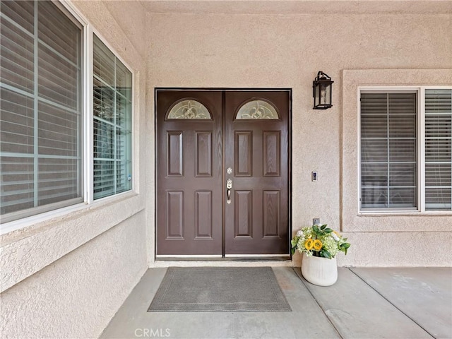 property entrance with covered porch and stucco siding