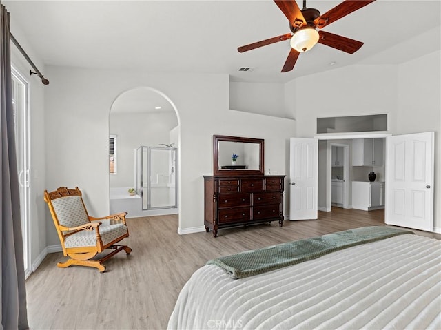 bedroom featuring baseboards, arched walkways, wood finished floors, and multiple windows