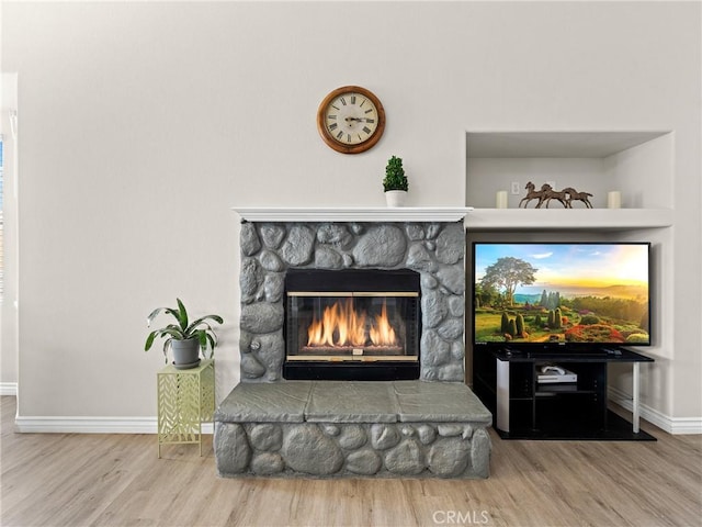 interior details featuring baseboards, a fireplace, and wood finished floors