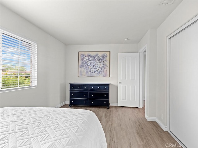 bedroom featuring baseboards, wood finished floors, and visible vents
