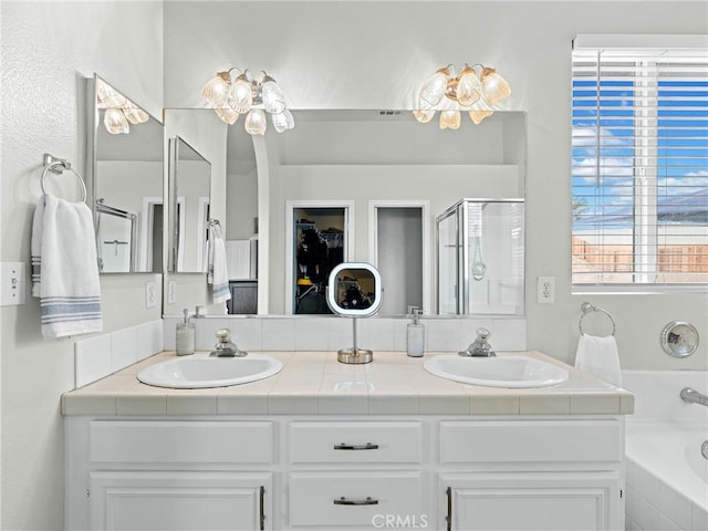 full bathroom featuring a sink, a bath, a stall shower, and double vanity