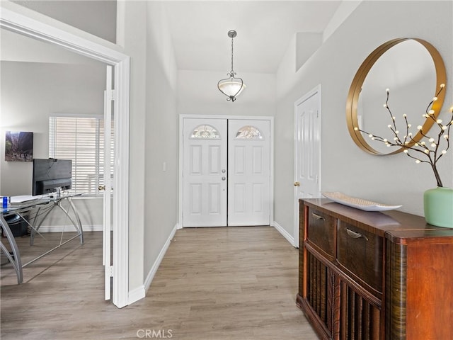 entryway with baseboards, an inviting chandelier, and light wood-style flooring