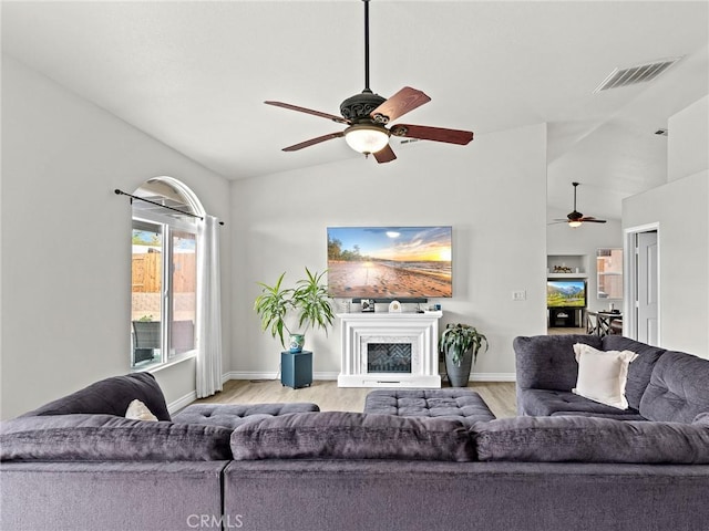 living room featuring visible vents, light wood finished floors, ceiling fan, and vaulted ceiling
