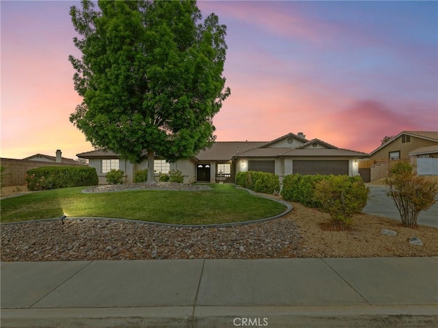 ranch-style house featuring fence, a garage, a tiled roof, a yard, and driveway