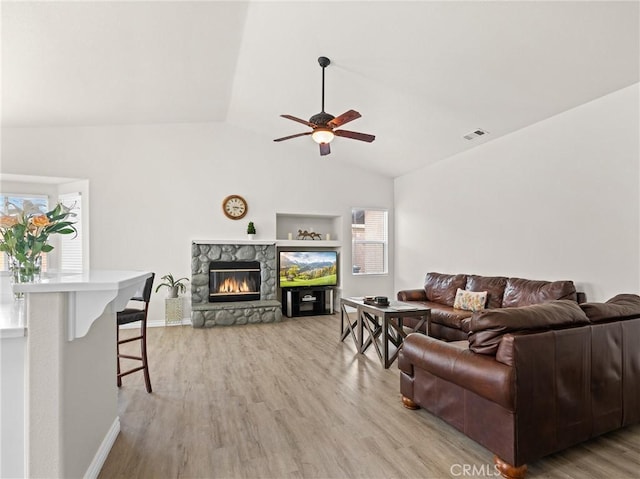 living room with ceiling fan, a fireplace, light wood-style flooring, lofted ceiling, and visible vents