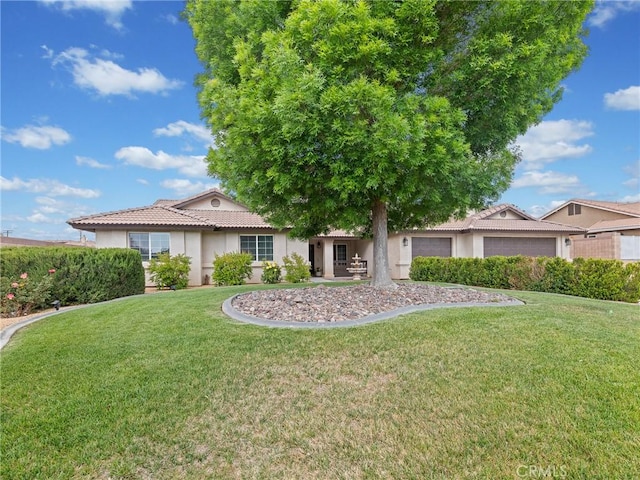 view of front of home featuring a tiled roof, a garage, a front lawn, and stucco siding