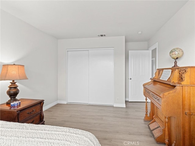 bedroom with baseboards, a closet, light wood-style flooring, and visible vents