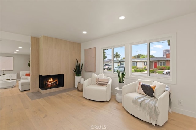 living area with light wood-type flooring, recessed lighting, a multi sided fireplace, and baseboards