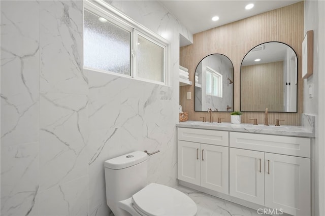 full bath with double vanity, a sink, marble finish floor, and toilet