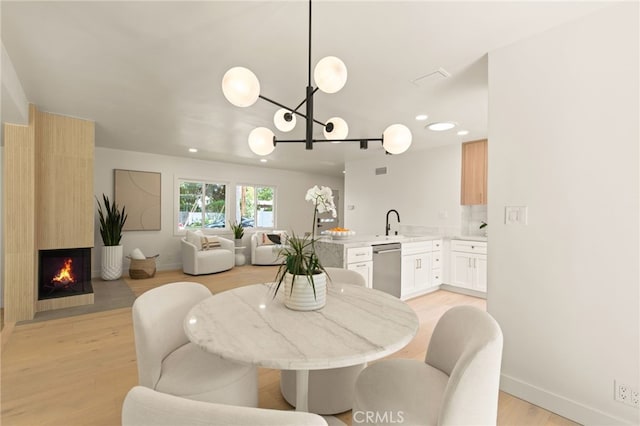 dining room featuring an inviting chandelier, a fireplace, baseboards, light wood-type flooring, and recessed lighting