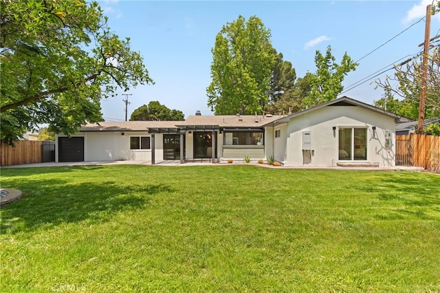 rear view of property with an attached garage, fence, and a yard
