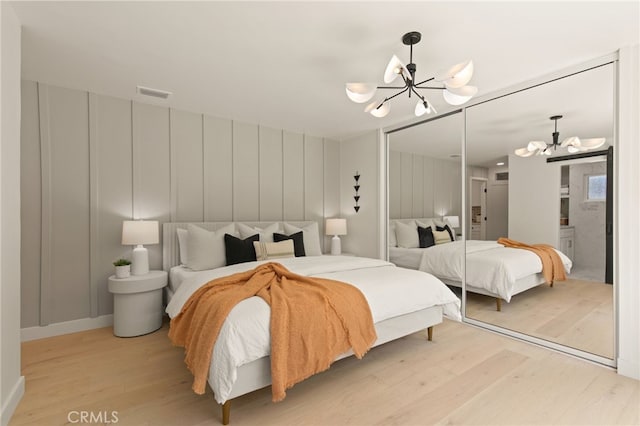 bedroom with an inviting chandelier, visible vents, a closet, and light wood-type flooring