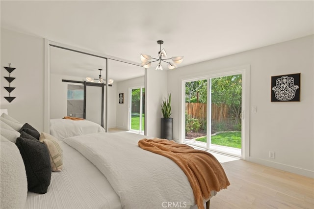 bedroom featuring access to exterior, a barn door, baseboards, an inviting chandelier, and light wood-style flooring