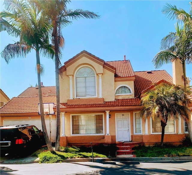 mediterranean / spanish-style house featuring a garage, a tile roof, and stucco siding