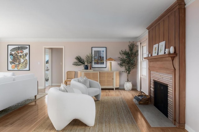 living room featuring baseboards, ornamental molding, light wood finished floors, and a fireplace