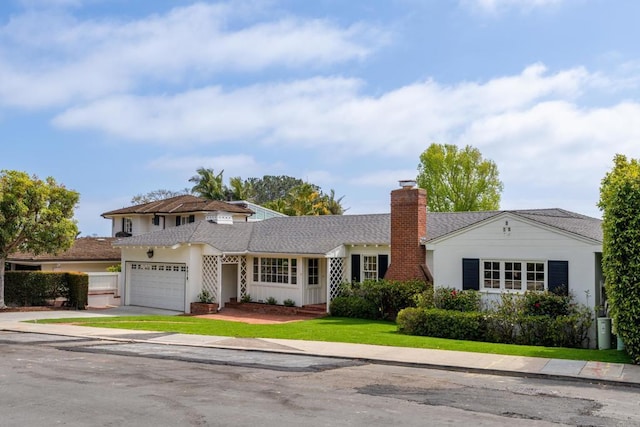 traditional home featuring concrete driveway, an attached garage, a chimney, and a front lawn
