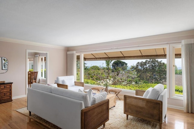 living area with light wood-style floors, ornamental molding, and baseboards