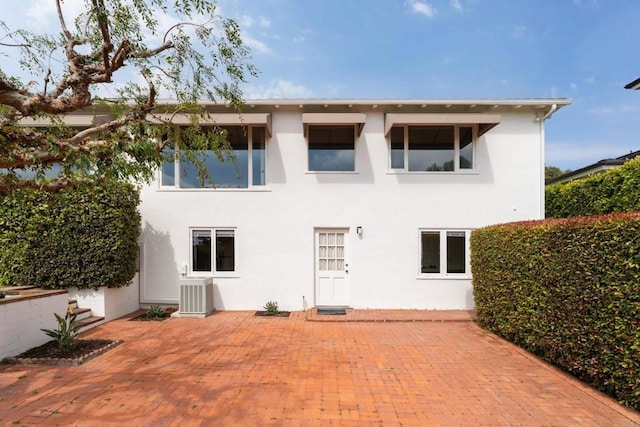 back of property featuring central AC unit, stucco siding, and a patio