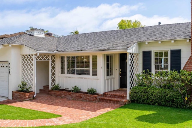 view of front of house with a garage, board and batten siding, a shingled roof, and a front lawn