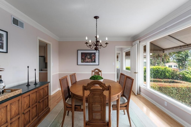 dining space with a notable chandelier, baseboards, light wood-type flooring, visible vents, and ornamental molding