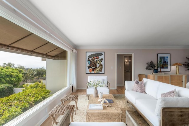 living area featuring light wood-type flooring, ornamental molding, and baseboards