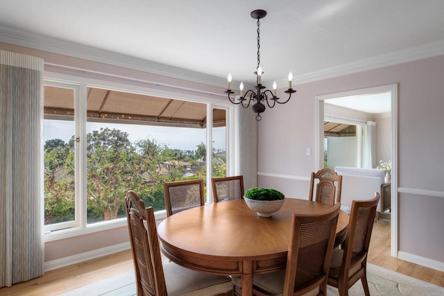 dining space featuring baseboards, light wood-style flooring, crown molding, and a chandelier
