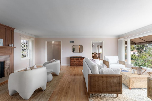 living area featuring a healthy amount of sunlight, crown molding, a fireplace, and light wood-type flooring