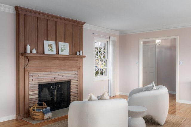 living room with a large fireplace, baseboards, ornamental molding, and light wood-type flooring