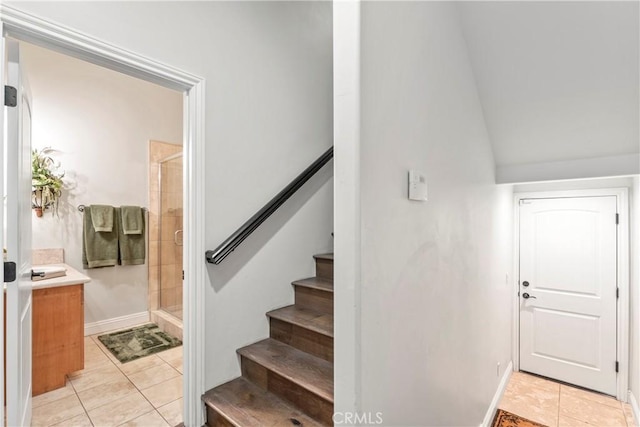 staircase with baseboards, tile patterned flooring, and lofted ceiling